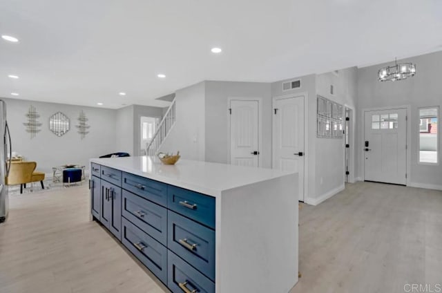 kitchen with an inviting chandelier, a healthy amount of sunlight, light hardwood / wood-style floors, and a kitchen island