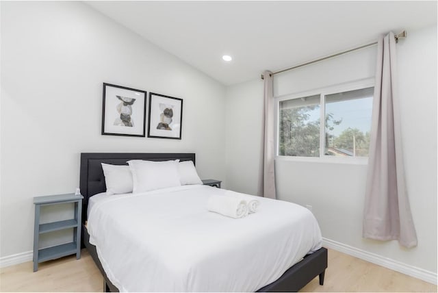 bedroom with vaulted ceiling and light hardwood / wood-style flooring