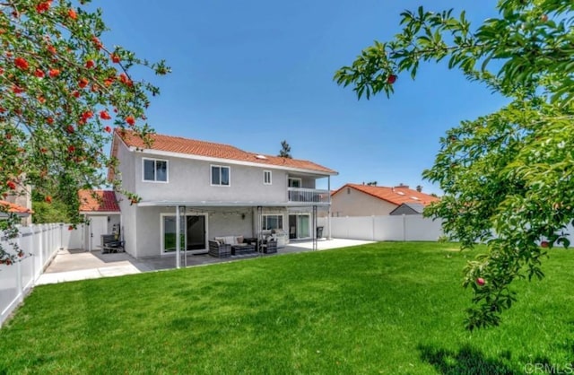 back of property with a balcony, outdoor lounge area, a patio area, and a lawn