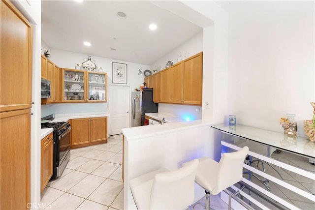 kitchen with appliances with stainless steel finishes, a kitchen breakfast bar, kitchen peninsula, and light tile patterned floors