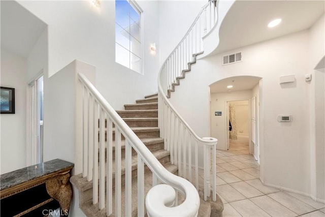 stairs with tile patterned flooring and a high ceiling