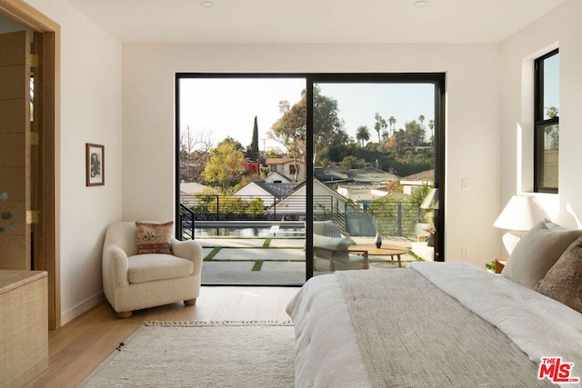 bedroom with multiple windows, access to exterior, and light hardwood / wood-style floors