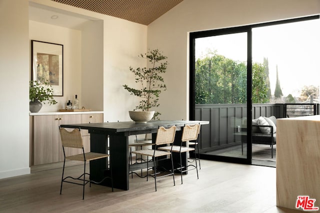 dining area featuring hardwood / wood-style floors and vaulted ceiling