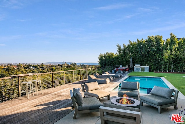 view of pool with area for grilling, an outdoor living space with a fire pit, and a deck