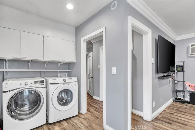 laundry room featuring crown molding, cabinets, washer and clothes dryer, and light hardwood / wood-style floors