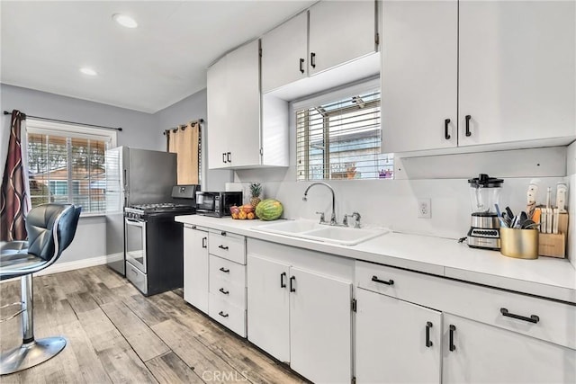 kitchen with white cabinetry, sink, light hardwood / wood-style floors, and appliances with stainless steel finishes