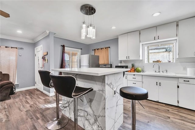 kitchen with pendant lighting, sink, stainless steel fridge, and white cabinets