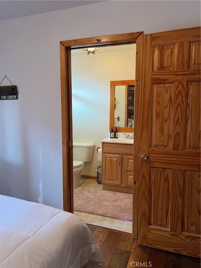 bedroom featuring hardwood / wood-style flooring, ensuite bathroom, and sink