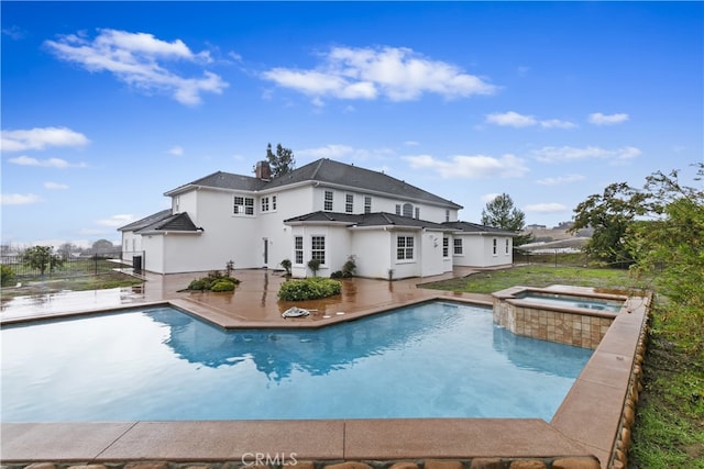 outdoor pool with a patio area, fence, and an in ground hot tub