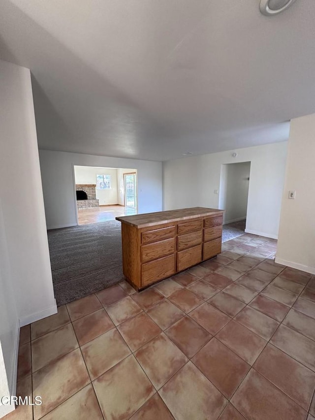 kitchen featuring baseboards, brown cabinetry, open floor plan, tile patterned floors, and a peninsula