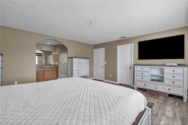 unfurnished bedroom featuring sink, connected bathroom, and light hardwood / wood-style flooring