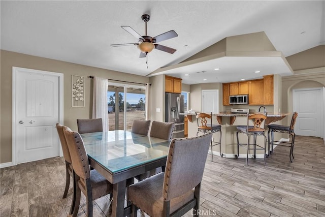 dining area featuring lofted ceiling, ceiling fan, and light wood-type flooring