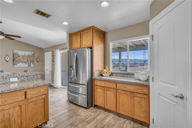 kitchen with light stone counters, vaulted ceiling, stainless steel fridge with ice dispenser, light wood-type flooring, and ceiling fan