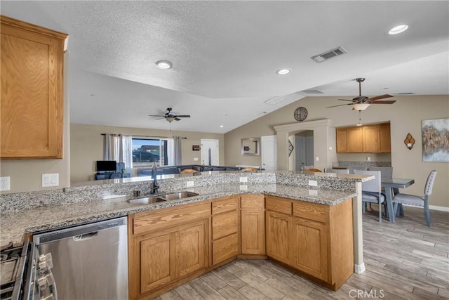 kitchen with vaulted ceiling, appliances with stainless steel finishes, sink, kitchen peninsula, and light hardwood / wood-style flooring