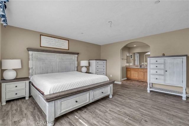 bedroom featuring hardwood / wood-style flooring and connected bathroom