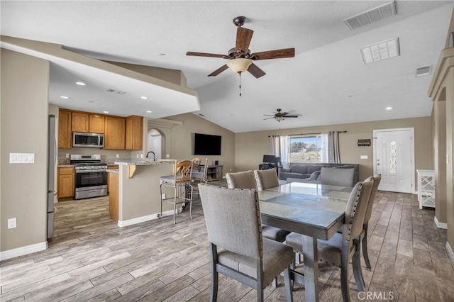 dining room with vaulted ceiling, sink, ceiling fan, and light hardwood / wood-style floors