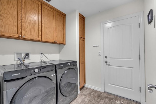 clothes washing area featuring cabinets, wood-type flooring, and independent washer and dryer