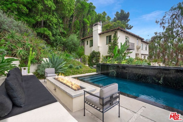 view of swimming pool featuring a patio and a fire pit