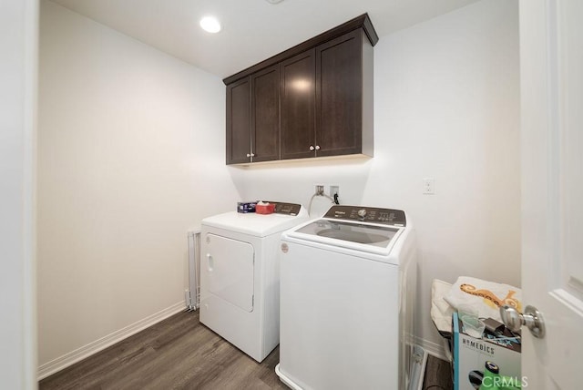 clothes washing area featuring cabinets, dark hardwood / wood-style floors, and washer and clothes dryer