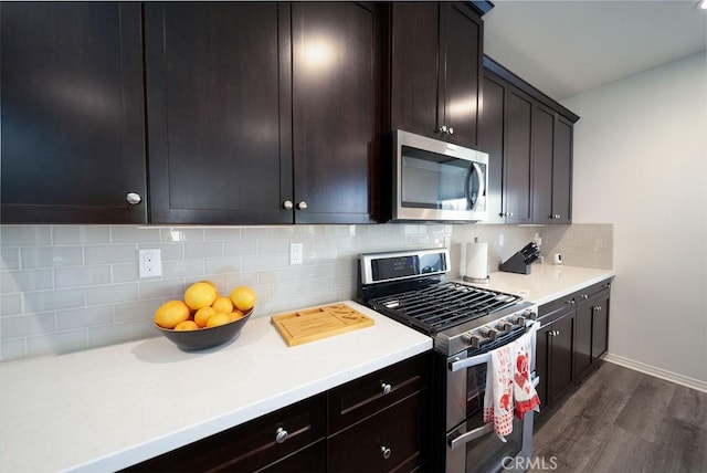 kitchen featuring stainless steel appliances, dark brown cabinets, dark hardwood / wood-style floors, and backsplash