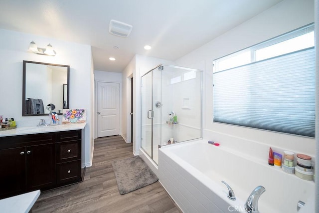 bathroom featuring hardwood / wood-style flooring, vanity, and shower with separate bathtub