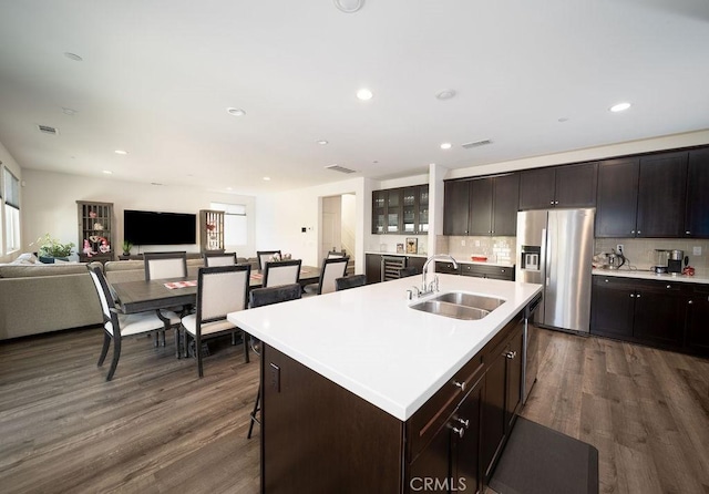 kitchen with dark wood-type flooring, appliances with stainless steel finishes, sink, and an island with sink