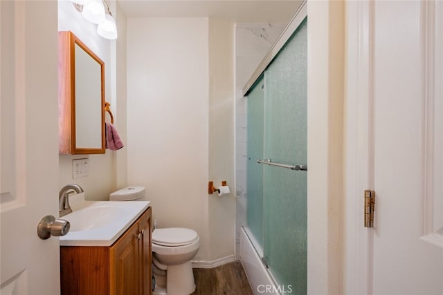 full bathroom with vanity, hardwood / wood-style flooring, bath / shower combo with glass door, and toilet