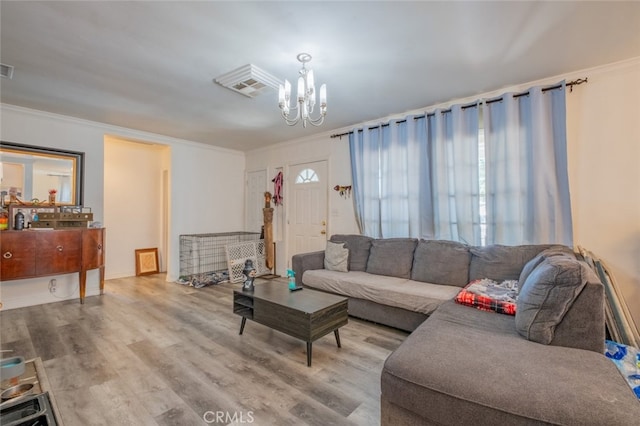 living room featuring hardwood / wood-style flooring, ornamental molding, and an inviting chandelier