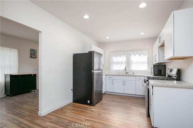 kitchen with white cabinetry, sink, stainless steel appliances, and light hardwood / wood-style floors