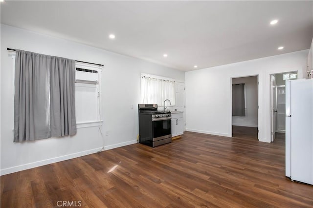 kitchen featuring stainless steel range with gas cooktop, white cabinetry, sink, dark hardwood / wood-style flooring, and white fridge