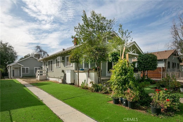 view of front of home featuring a wall unit AC and a front yard