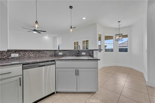 kitchen with sink, tasteful backsplash, light tile patterned floors, stainless steel dishwasher, and dark stone counters