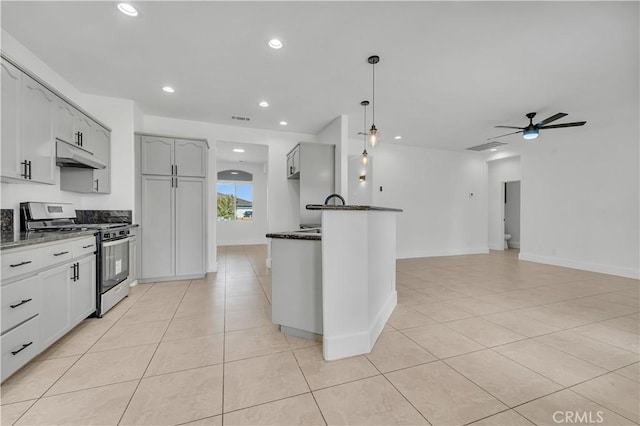 kitchen featuring hanging light fixtures, stainless steel range with gas cooktop, dark stone countertops, and ceiling fan