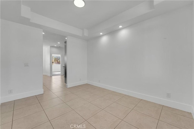 spare room featuring light tile patterned floors and a raised ceiling