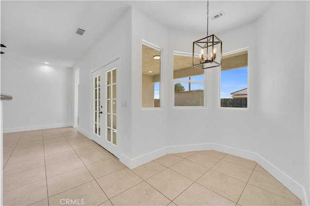 unfurnished dining area featuring a notable chandelier, french doors, and light tile patterned flooring