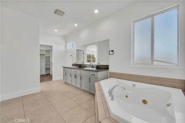 bathroom featuring vanity, tile patterned flooring, and tiled tub