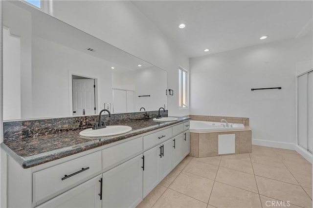 bathroom featuring tile patterned flooring, vanity, and tiled bath