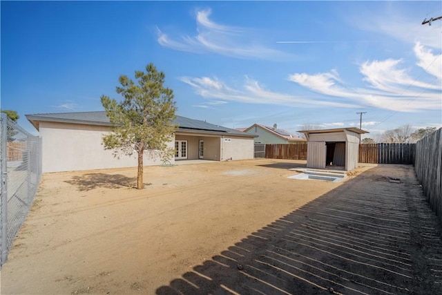 rear view of property featuring solar panels and a storage unit