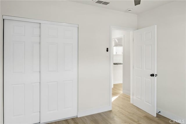 unfurnished bedroom with light hardwood / wood-style flooring, a closet, and ceiling fan