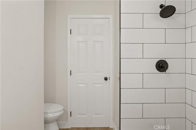 bathroom featuring a tile shower and toilet