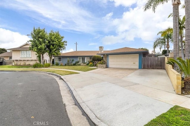 ranch-style home featuring driveway, a garage, fence, and a front yard