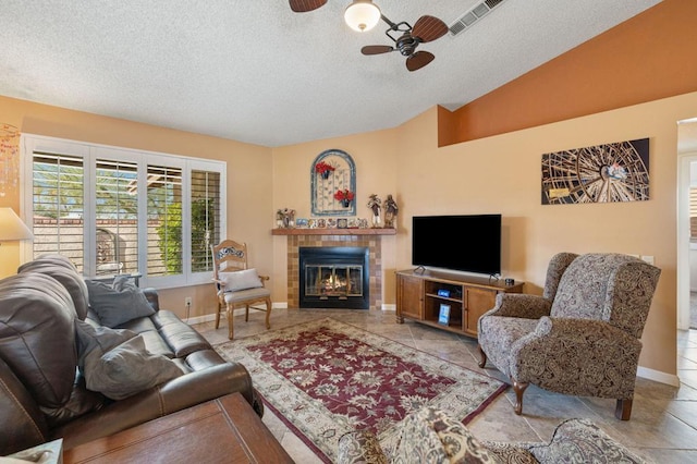 living room with a tile fireplace, vaulted ceiling, ceiling fan, and a textured ceiling