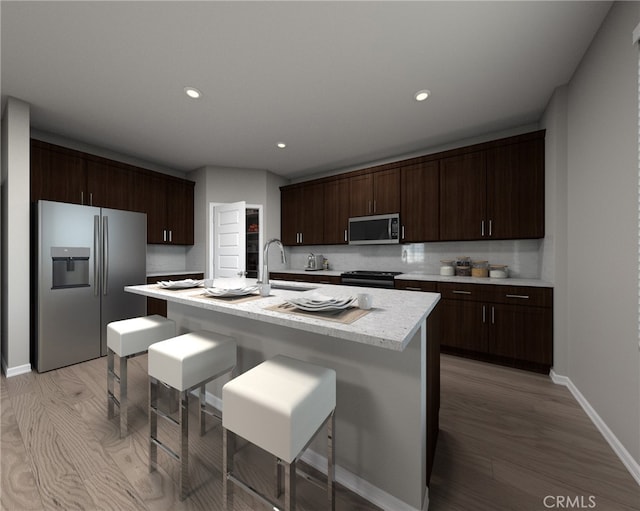 kitchen with an island with sink, appliances with stainless steel finishes, sink, and dark brown cabinets