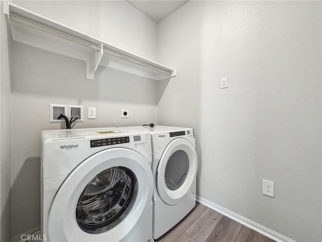 washroom featuring laundry area, washer and clothes dryer, wood finished floors, and baseboards