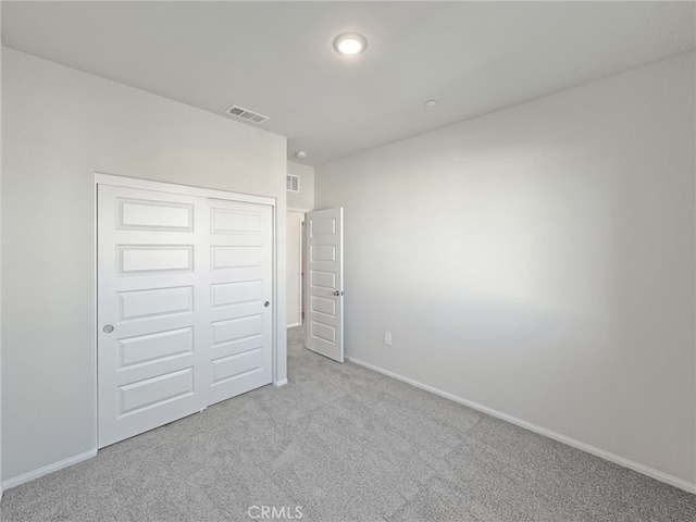 unfurnished bedroom featuring carpet floors, a closet, visible vents, and baseboards