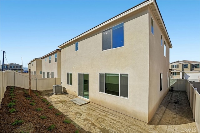 back of property with a fenced backyard, cooling unit, and stucco siding