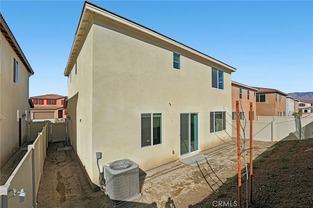 back of property with stucco siding, a fenced backyard, and central AC unit