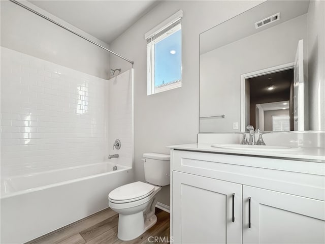 bathroom with visible vents, toilet, tub / shower combination, vanity, and wood finished floors