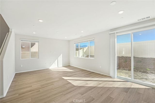 spare room featuring baseboards, light wood-type flooring, visible vents, and recessed lighting