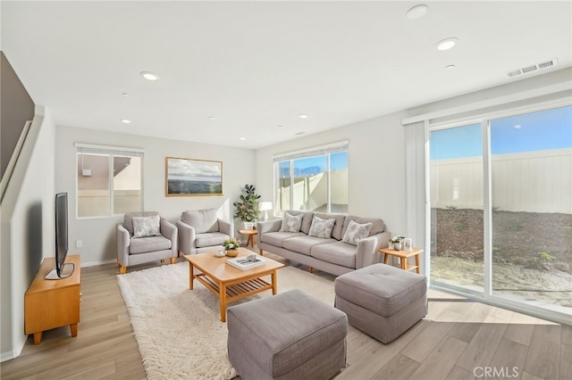 living room with recessed lighting, visible vents, light wood-style flooring, and baseboards